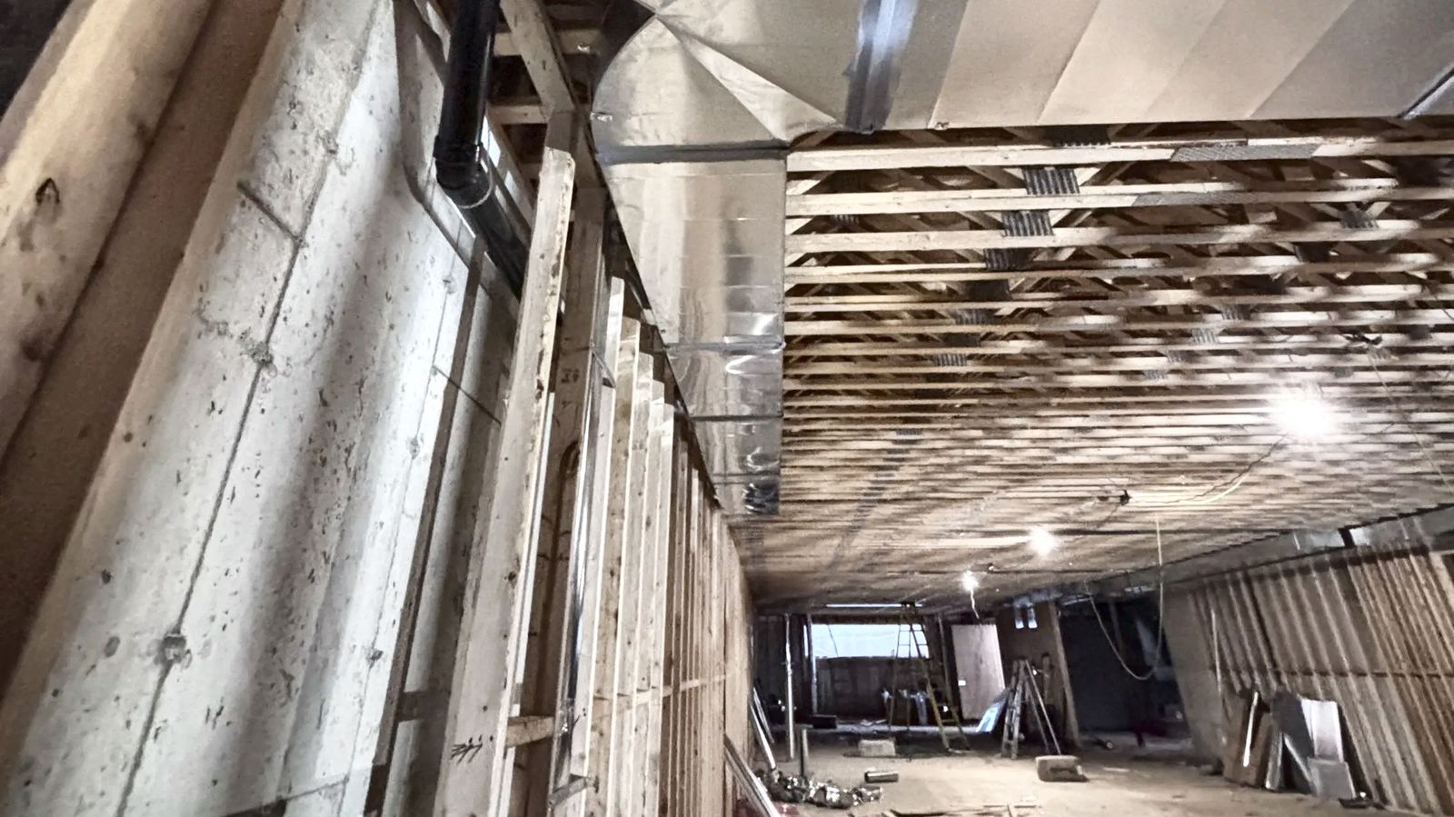 Trunk elbow and long duct run through a multi-unit basement during rough-in